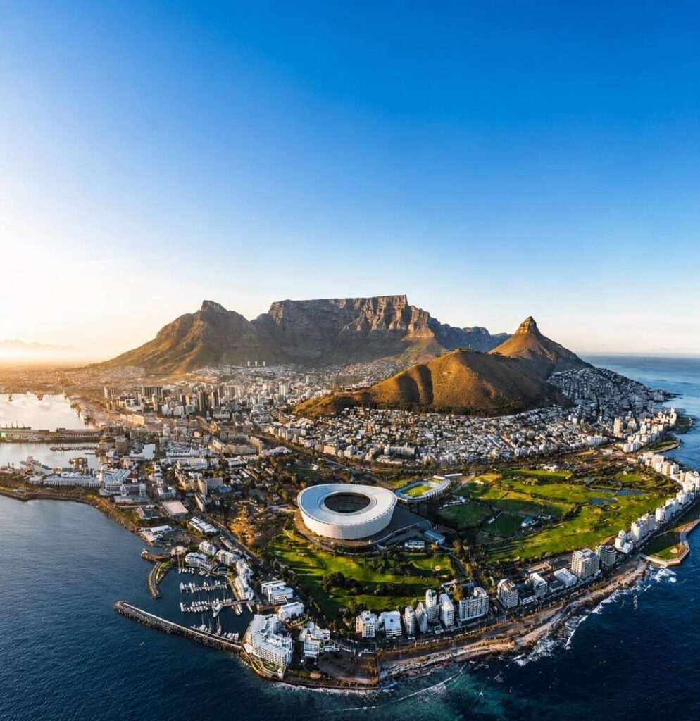 Table Mountain and Cape Town city skyline overlooking the blue ocean coastline.