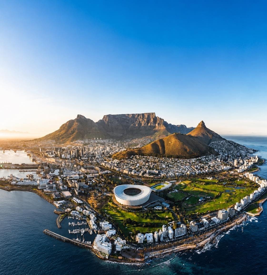 Table Mountain and Cape Town city skyline overlooking the blue ocean coastline.