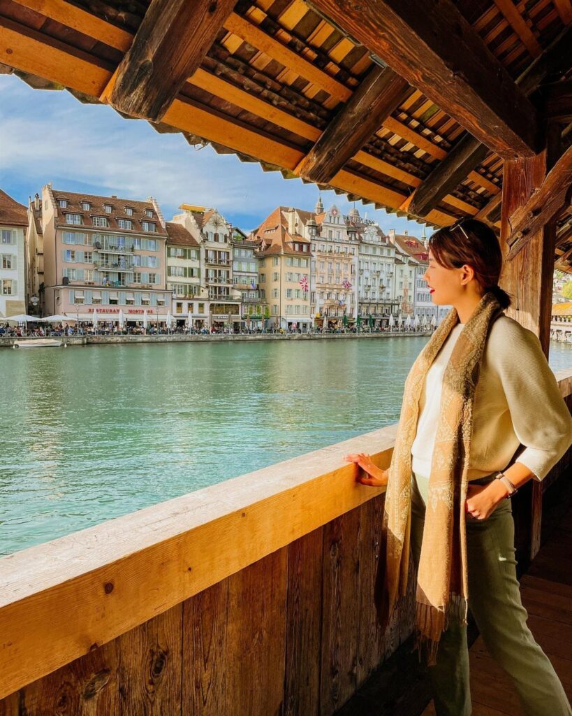 Woman on the Chapel Bridge looking at colorful buildings across Lake Lucerne