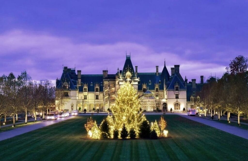 Large historic stone estate with a massive glowing Christmas tree on the front lawn