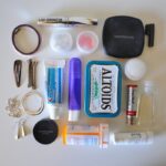 Travel-sized toiletries and personal care items arranged on a plain white background.