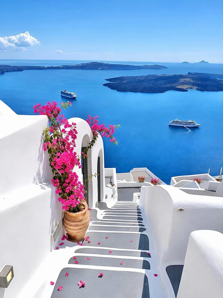 White buildings and pink flowers overlooking the blue sea and islands in Greece.