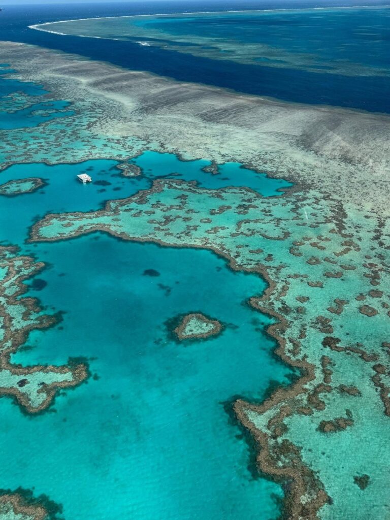 Aerial view of turquoise lagoons and coral reefs in a deep blue ocean.
