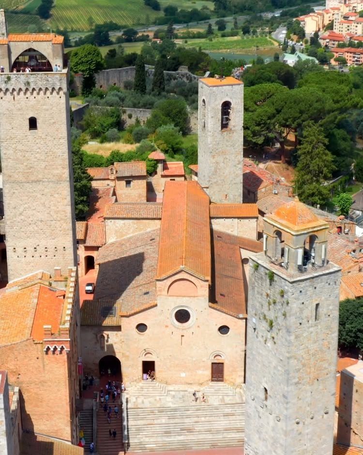 Medieval stone buildings and towers with terracotta roofs in a historic Italian city.