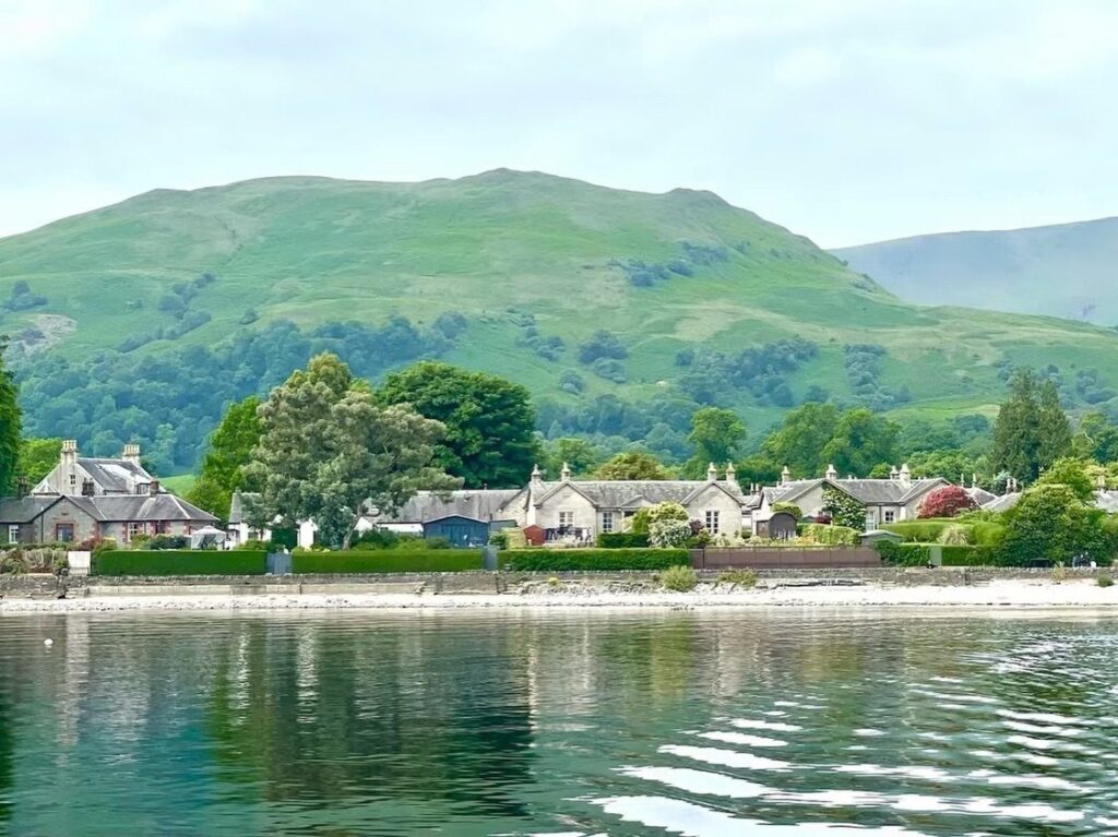 Lakeside village with stone houses and rolling green hills in Scotland