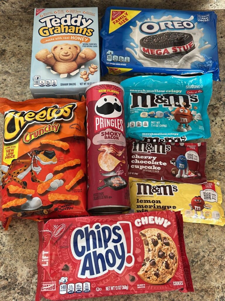 Assorted packaged snacks including cookies, chips, and candies on a granite countertop.