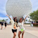 Two women posing in front of the Spaceship Earth sphere at Epcot Orlando.