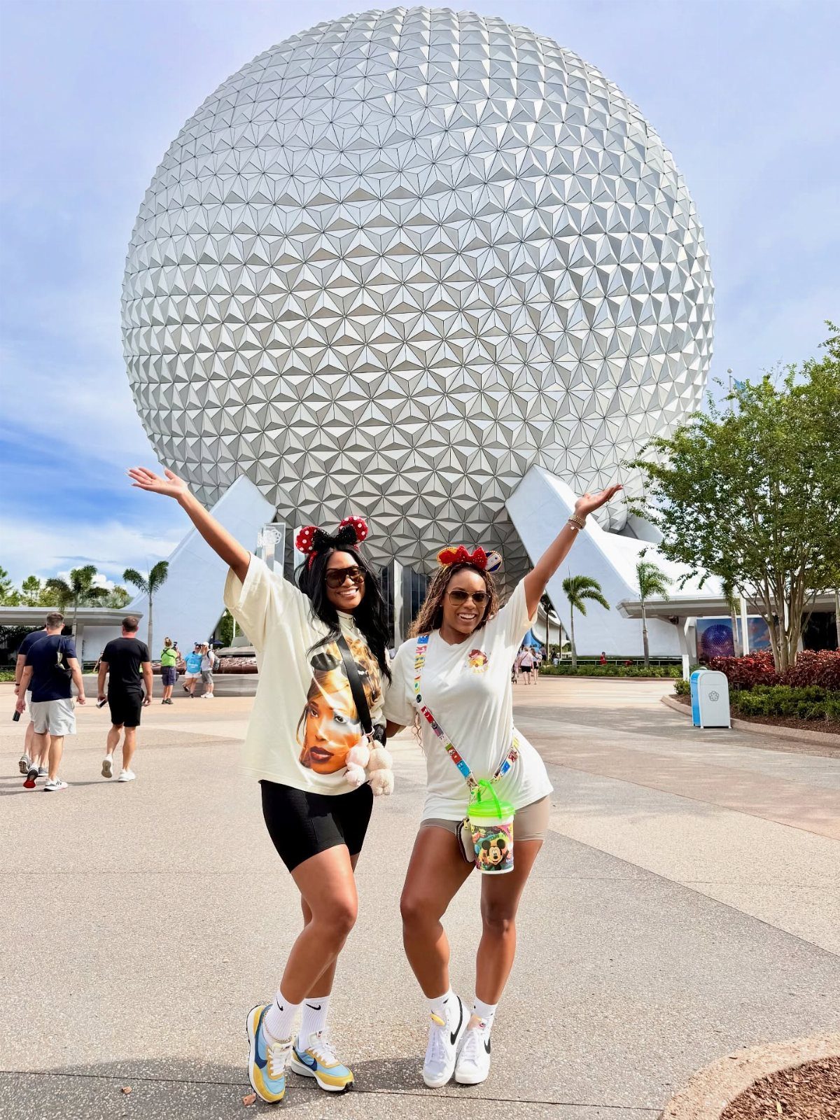 Two women posing in front of the Spaceship Earth sphere at Epcot Orlando.