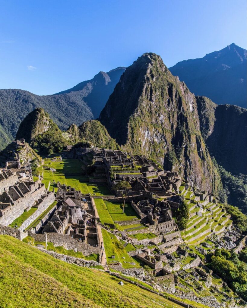 Ancient stone ruins of Machu Picchu nestled among steep green mountains and peaks.